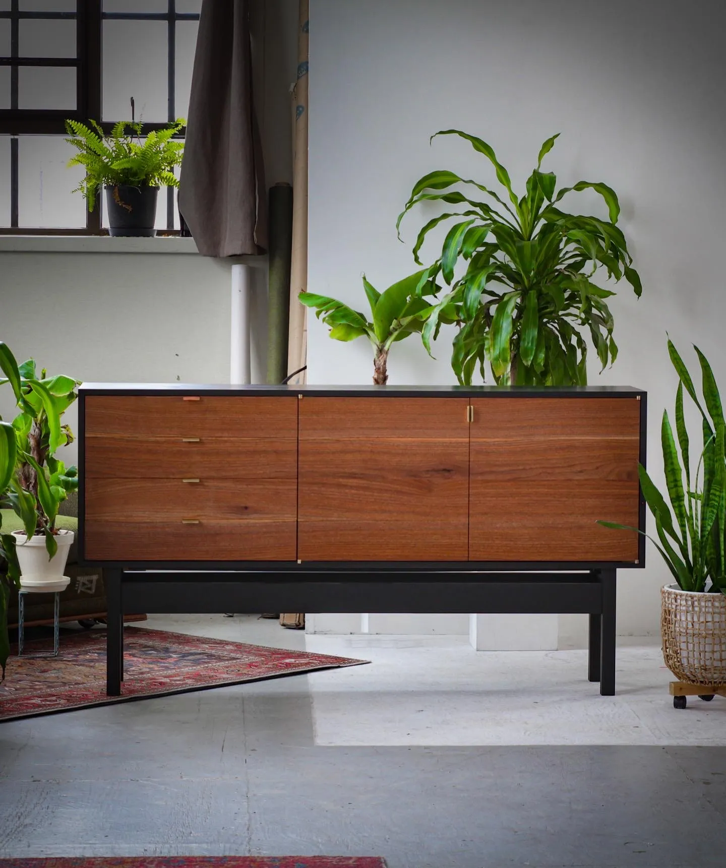 The credenza viewed straight on, doors and drawers closed, showing the run of walnut grain across the fronts.
