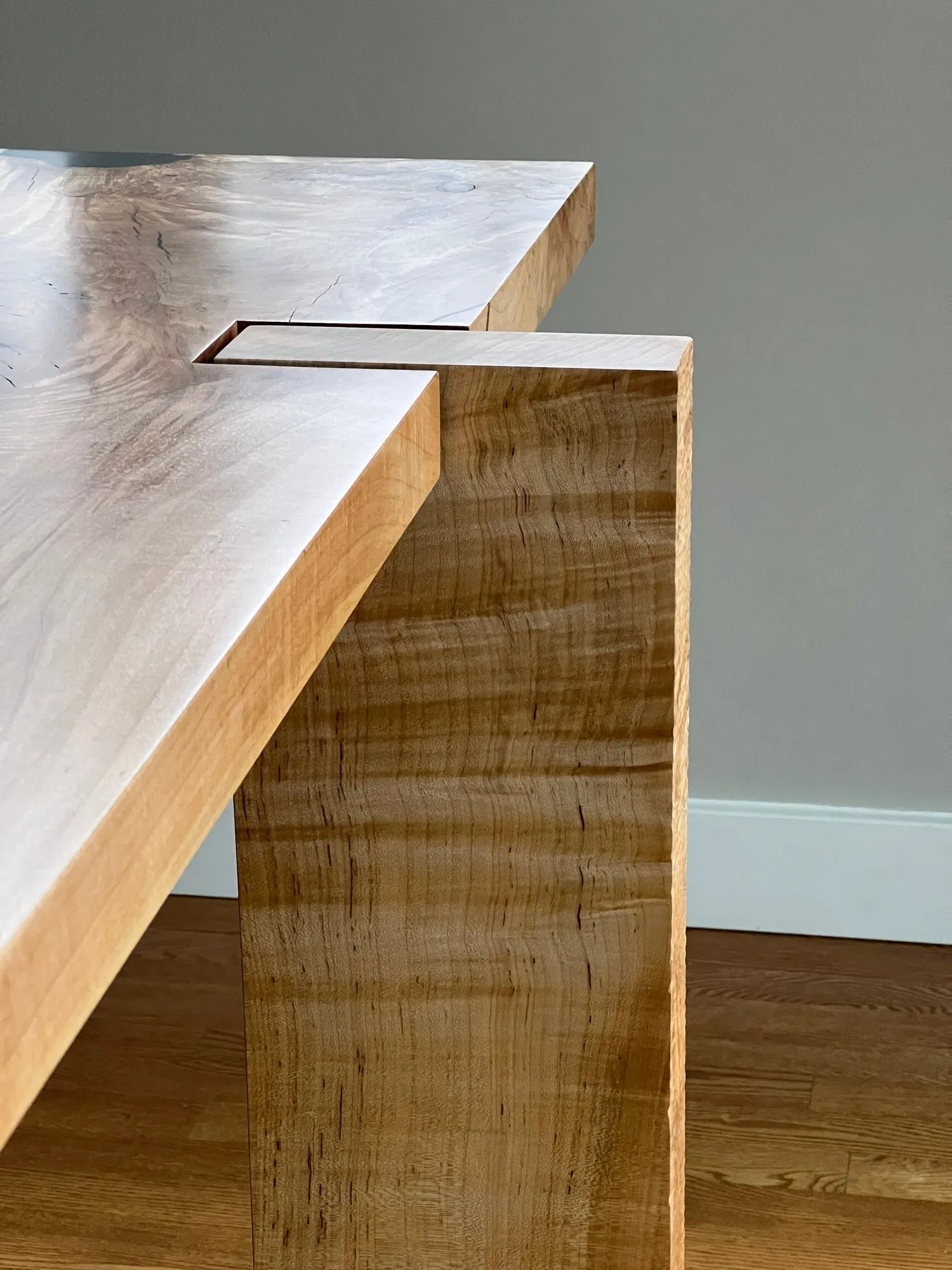 Close view of the joinery where a silver maple cross member passes through a stretcher as an exposed through-tenon.