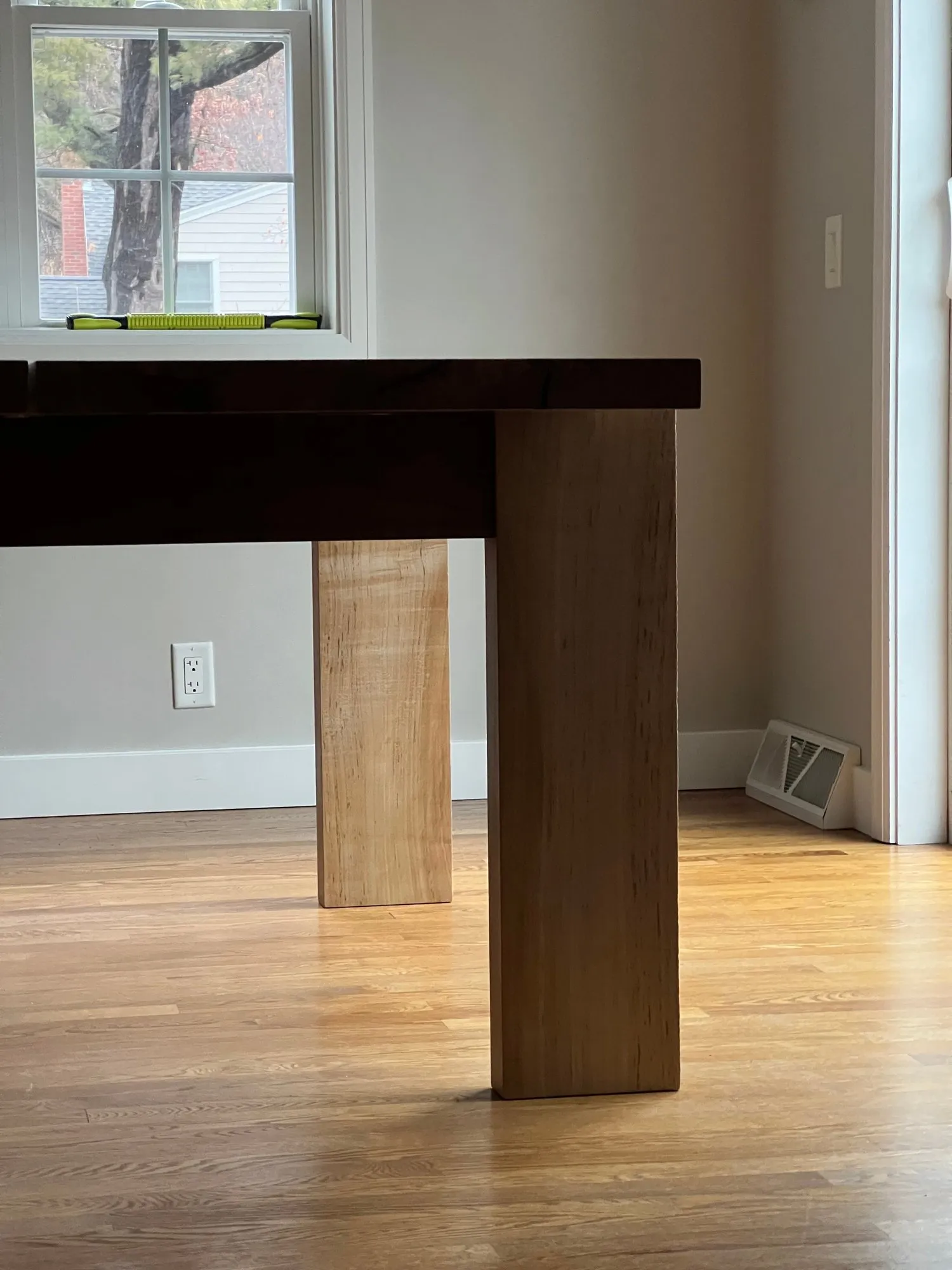 A corner of the table showing a figured silver maple leg meeting the apron above it.