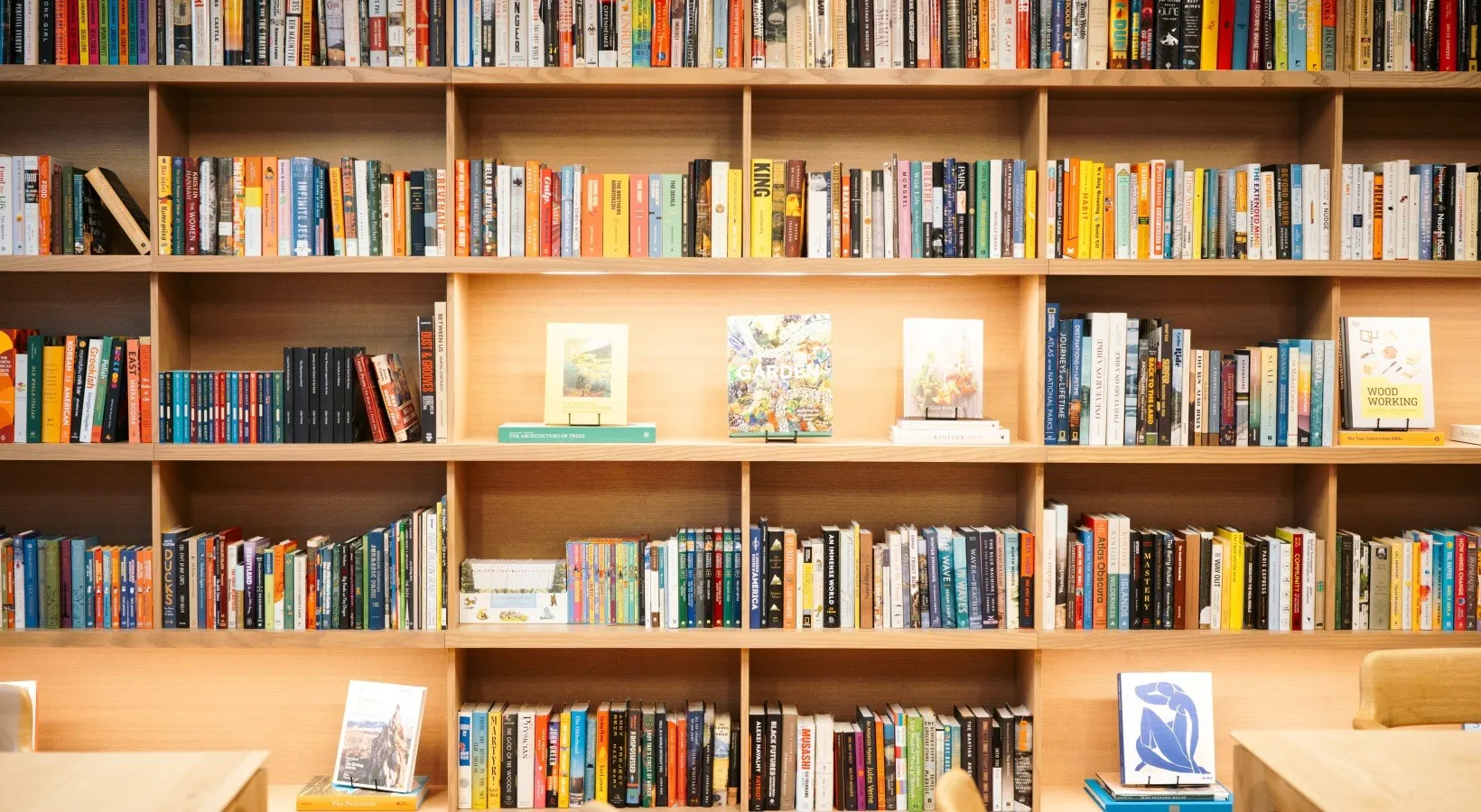 A close view of the built-in oak library shelving, filled with books and face-out display titles.