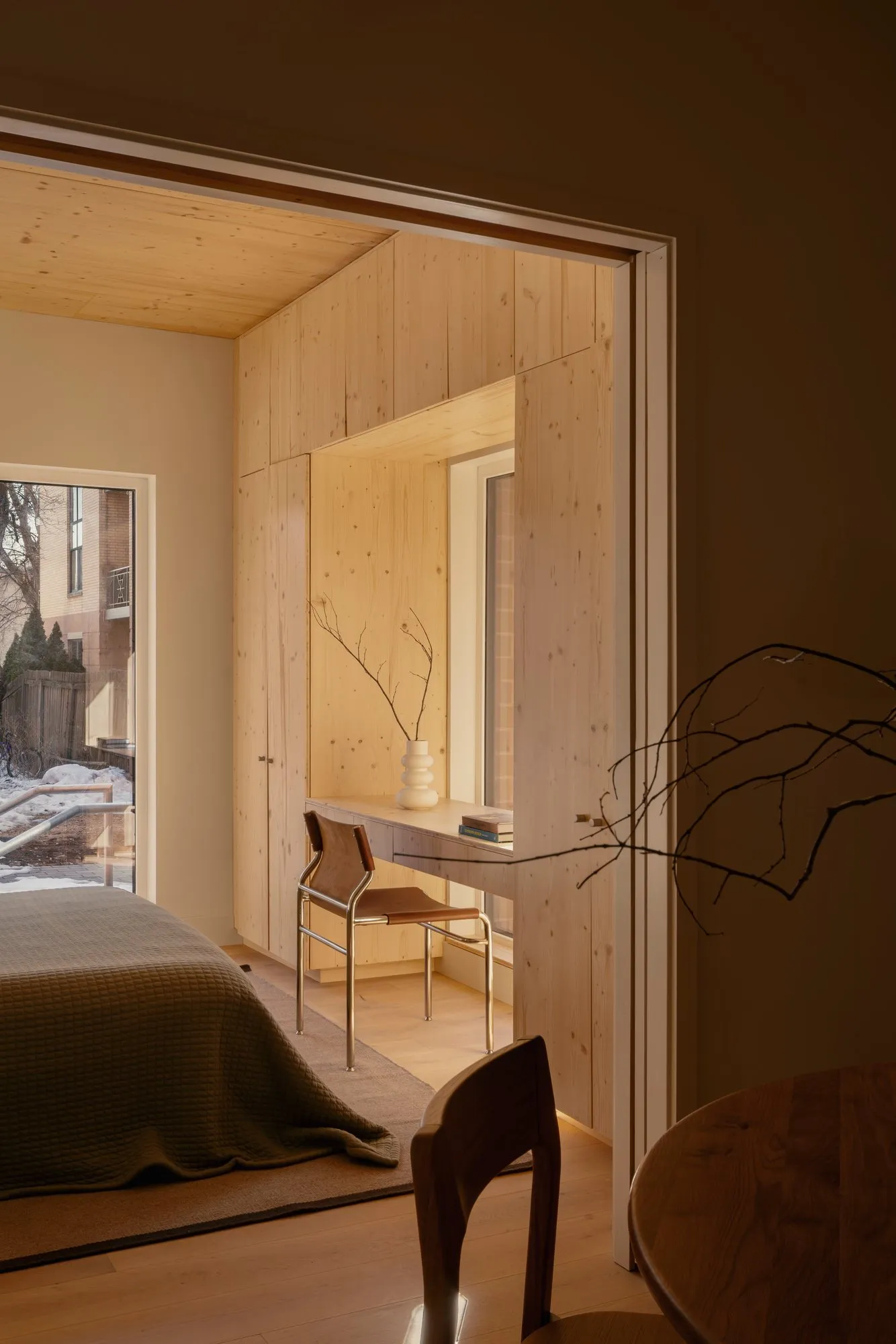 Looking through to the bedroom, where a pine desk is built into a window reveal beside the wardrobes.