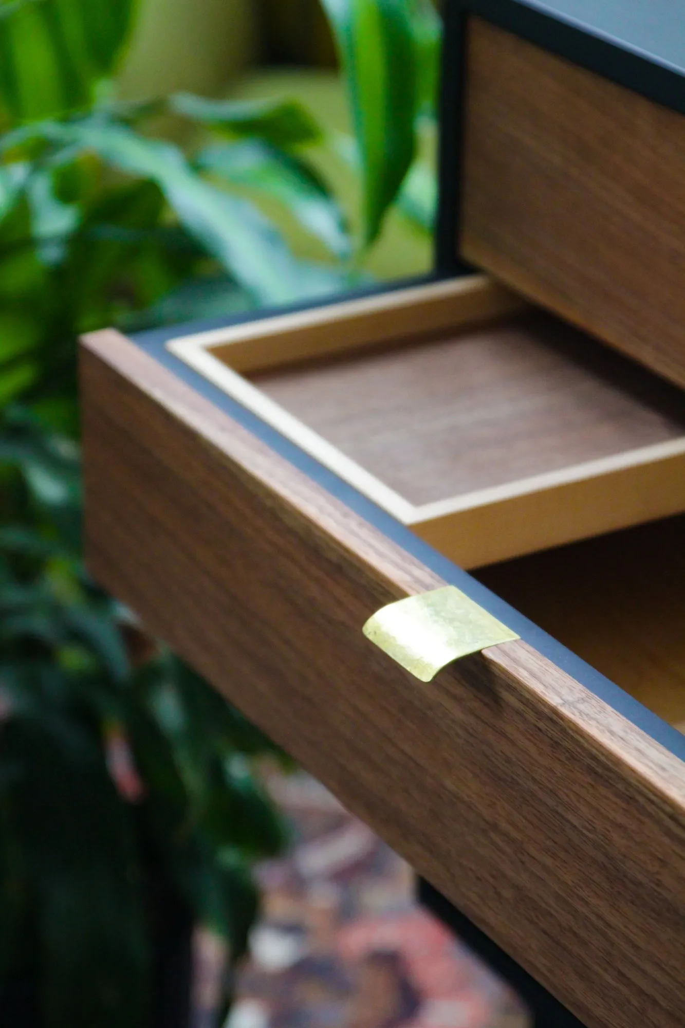 An open drawer with a maple-lined valet tray and a hand-shaped brass pull catching the light.