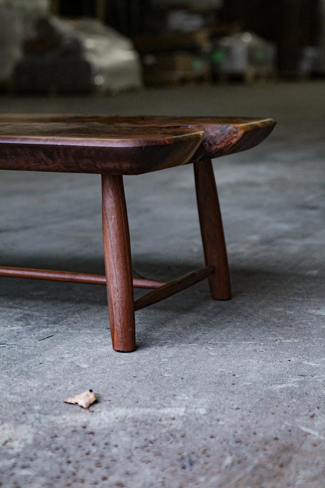 The turned tapered legs joined by slender stretchers beneath the corner of the walnut top.