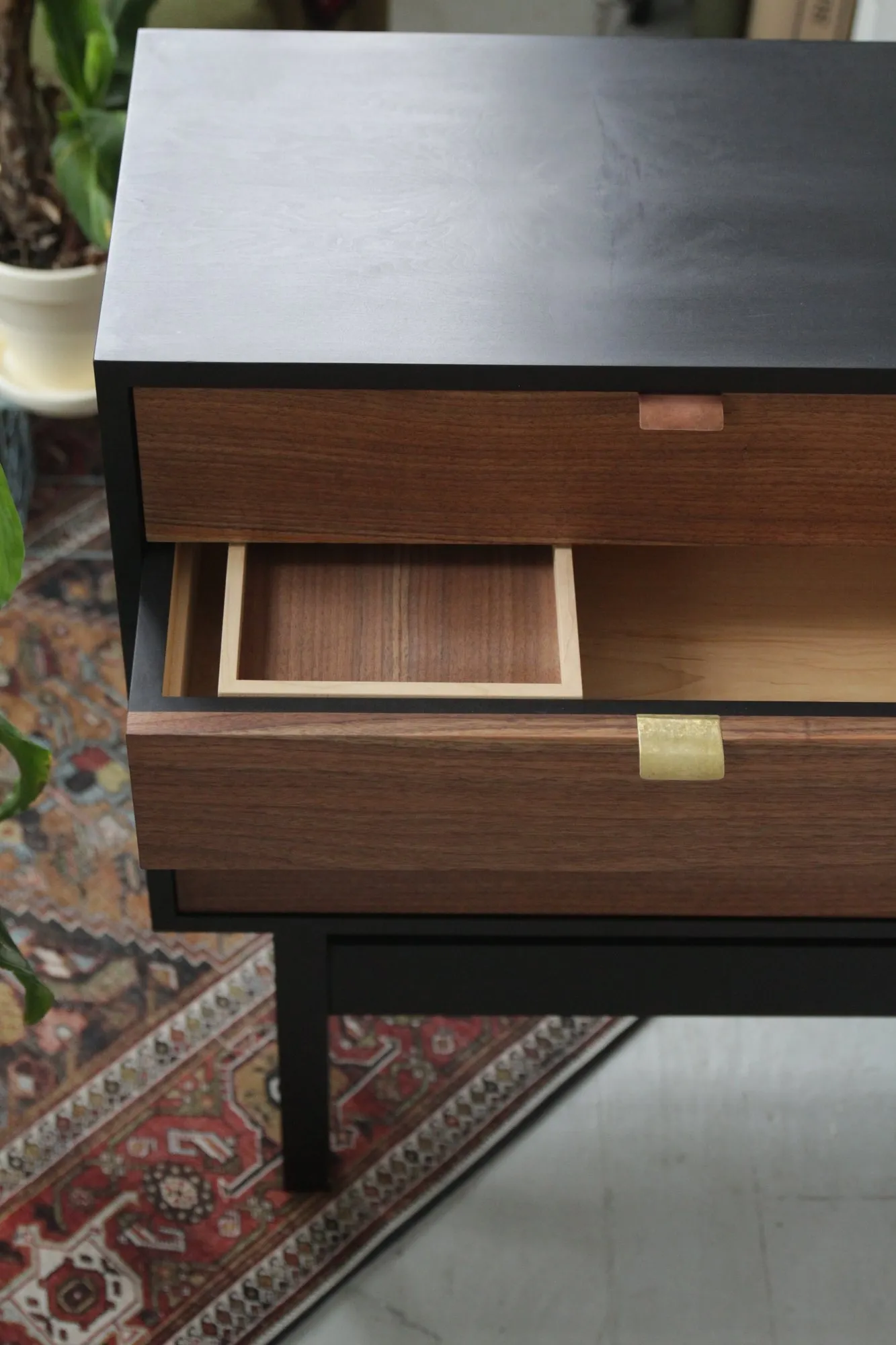 The upper corner with a door open, showing the walnut interior and a maple-lined drawer inside the case.