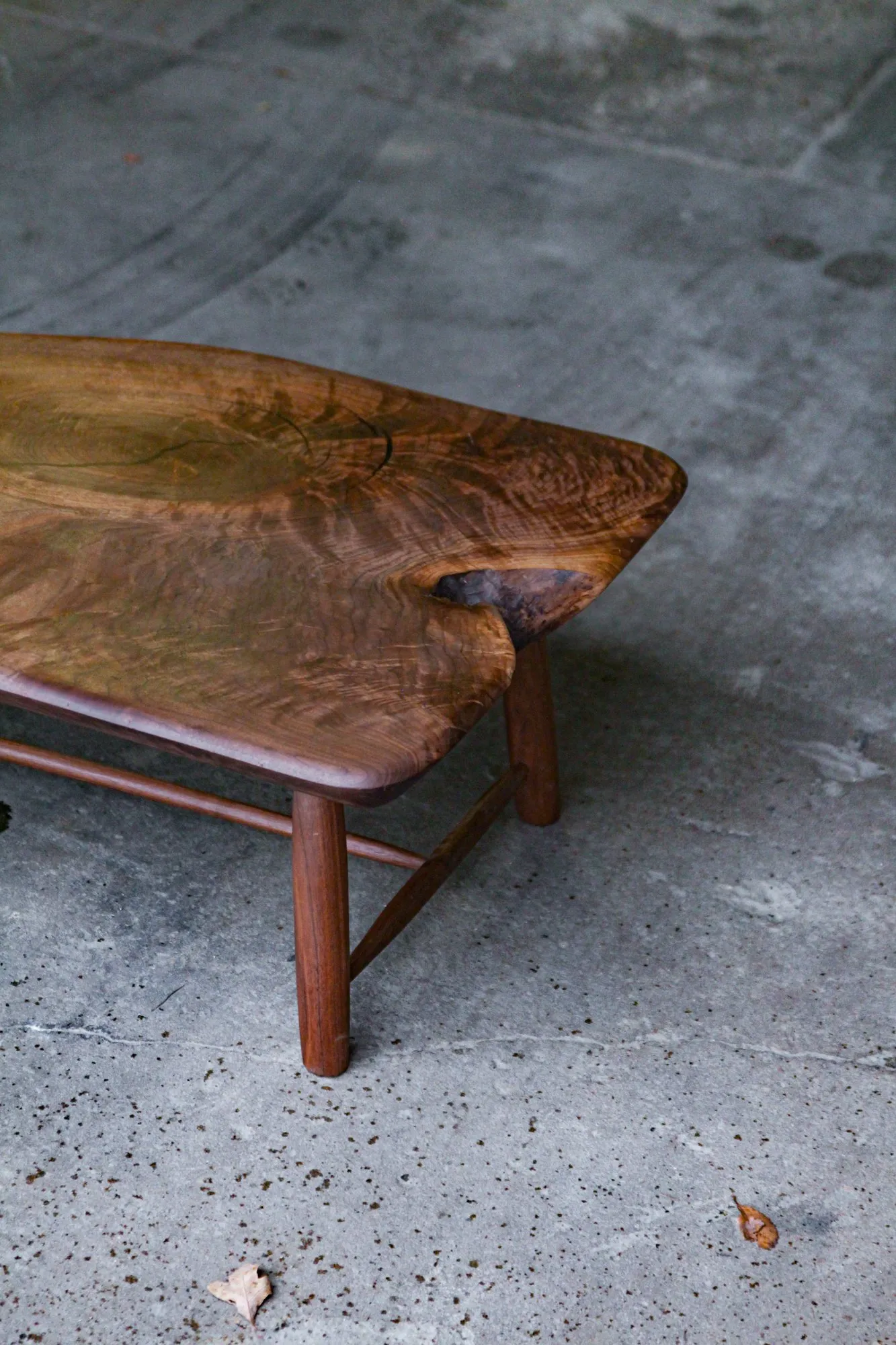 A three-quarter view of one end of the table, showing the thickness of the slab and the splay of the legs.