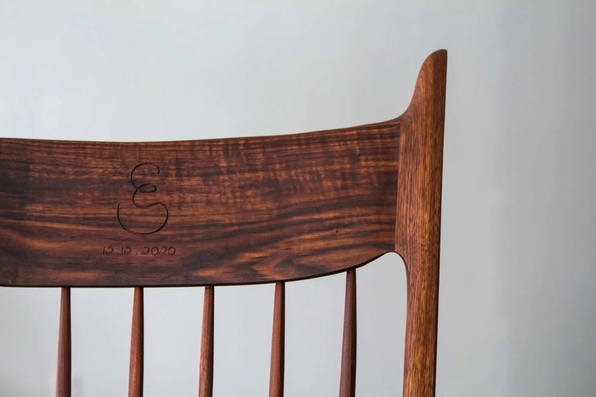 The figured walnut crest rail carved with a script monogram and the date 12.12.2020.